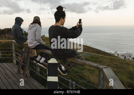 Skateboarder auf Geländer am Beobachtungspunkt sitzen Stockfoto