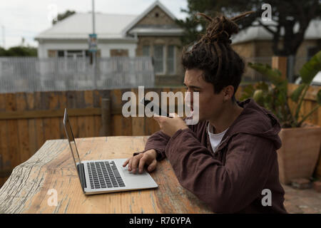 Männliche skateboarder Gespräch am Handy mit Laptop Stockfoto