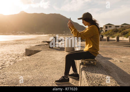 Frau Klick auf Foto mit Handy in der Nähe von Strand Stockfoto