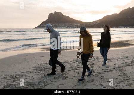 Skateboarder zu Fuß am Strand bei Sonnenuntergang Stockfoto