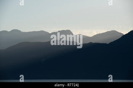 Die Sonnenstrahlen Gießen über die schön beleuchteten Berge der Coast Mountain Range in den späten Nachmittag. Stockfoto
