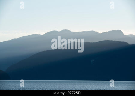 Die Sonnenstrahlen Gießen über die schön beleuchteten Berge der Coast Mountain Range in den späten Nachmittag. Stockfoto