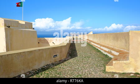 Die Wälle der Festung von Sagres (Fortaleza) mit dem Cabo de Sao Vicente (St Vincent Cape) Leuchtturm im Hintergrund, Sagres, Algarve, Portugal Stockfoto