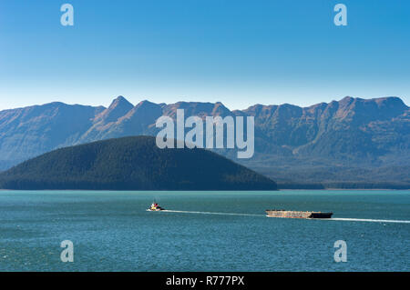 Tugboat ziehen Barge an einem sonnigen Tag in Gastineau Kanal, in der Nähe von Juneau, Alaska, USA. Douglas Insel im Hintergrund. Stockfoto