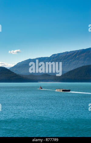 Tugboat ziehen Barge an einem sonnigen Tag in Gastineau Kanal, in der Nähe von Juneau, Alaska, USA. Douglas Insel im Hintergrund. Stockfoto