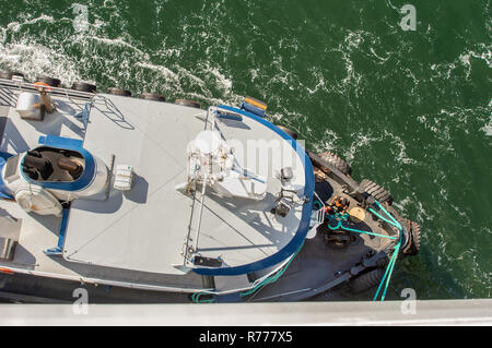 Overhead POV Blick auf Schleppdienste, Seile und Arbeitnehmer Unterstützung großes Schiff zu Dock bei starkem Wind auf einem hellen, sonnigen Tag. Gastineau Kanal, Juneau, Alaska, U Stockfoto