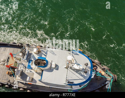 Overhead POV Blick auf Schleppdienste, Seile und Arbeitnehmer Unterstützung großes Schiff zu Dock bei starkem Wind auf einem hellen, sonnigen Tag. Gastineau Kanal, Juneau, Alaska, U Stockfoto