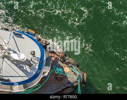 Overhead POV Blick auf Schleppdienste, Seile und Arbeitnehmer Unterstützung großes Schiff zu Dock bei starkem Wind auf einem hellen, sonnigen Tag. Gastineau Kanal, Juneau, Alaska, U Stockfoto