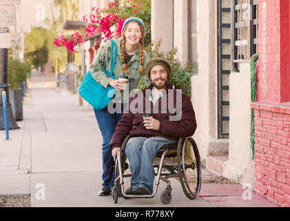 Frau mit blauen Kleid und der Mann im Rollstuhl Stockfoto