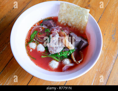 Nudeln mit Meeresfrüchten auf rote Suppe/heiß und würzig Thai Essen Nudeln mit Meeresfrüchten squid Schweinefleisch fisch Kugel und Morning glory knusprige Wan-tan Haut auf rote Soße Suppe Stockfoto