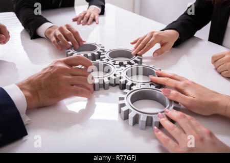 Geschäftsleute verbinden Zahnräder auf Schreibtisch Stockfoto