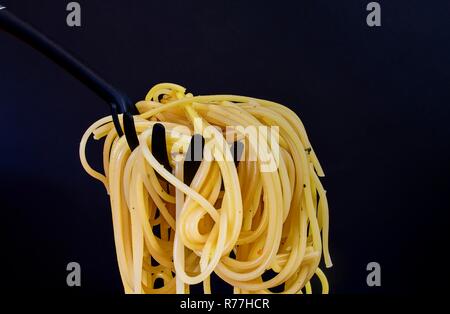 Gekochte Spaghetti auf Spaghetti Löffel. Spaghetti auf schwarzem Hintergrund. Close-up. Dunkle essen Foto. Platz kopieren Stockfoto