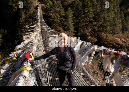 Nepal, Larja Dobhan, lächelnden älteren weiblichen Touristen am Ende der oberen Larja Hängebrücke über Dudh Khosi Fluss Stockfoto