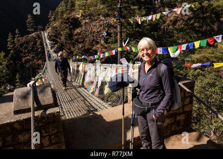 Nepal, Larja Dobhan, lächelnden älteren weiblichen Touristen am Ende der oberen Larja Hängebrücke über Dudh Khosi Fluss Stockfoto