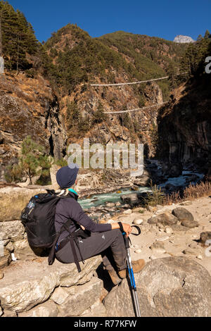 Nepal, Larja Dobhan, Senior weibliche Touristen auf dem Everest Base Camp Trek, ruht neben Dudh Khosi Fluss am oberen und unteren Larja Brücken Stockfoto