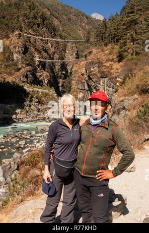 Nepal, Larja Dobhan, lächelnden älteren weiblichen Touristen mit Sherpa Guide an der oberen und unteren Larja Brücken über schnell fließenden Dudh Khosi Fluss Stockfoto