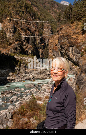 Nepal, Larja Dobhan, lächelnden älteren weiblichen Touristen, die sich am oberen und unteren Larja Brücken über schnell fließenden Dudh Khosi Fluss Stockfoto