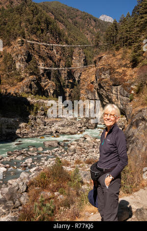 Nepal, Larja Dobhan, lächelnden älteren weiblichen Touristische an Larja Brücken über schnell fließenden Dudh Khosi Fluss Stockfoto