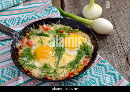 Spiegeleier mit grünen, Gemüse und Käse auf der Pfanne. Stockfoto