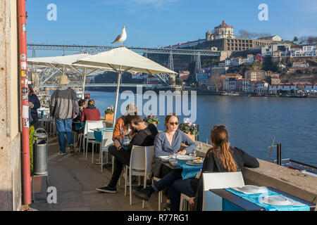 Porto, Portugal - Januar 19, 2018: Nicht identifizierte Personen mit Mittagessen im Café draußen am Ufer des Flusses Douro mit einem schönen Blick auf die Brücke Ponte do Stockfoto