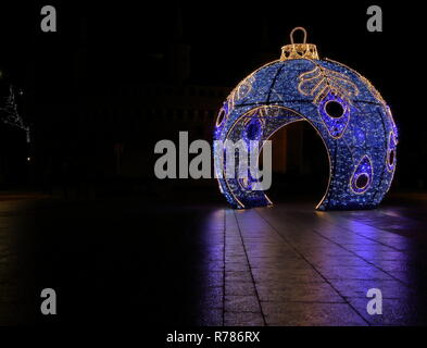 Schöne beleuchtete große Weihnachtskugel standson City Square bei Nacht, wunderbare Reflektionen auf nassem Boden Stockfoto