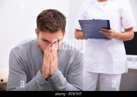 Nahaufnahme eines umgekippten junger Mann sitzt vor Arzt Holding Zwischenablage Stockfoto
