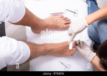 Hohe Betrachtungswinkel und der Kosmetikerin Befüllung des Menschen Nagel in Salon Stockfoto