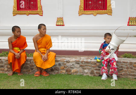 Zwei Neulinge und ein Junge, die eine Maske, Phi Ta Khon-masken Festival, in der Nähe von Wat Phon Chai, Amphoe Dan Sai, Provinz Loei, Thailand Stockfoto