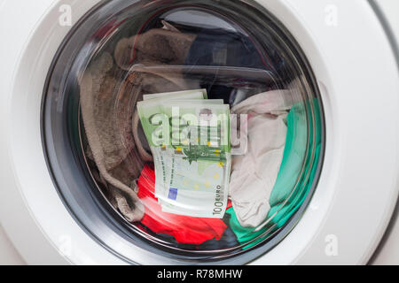 Geld in der Waschmaschine mit Wäsche beladen - Währung Euro Stockfoto