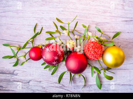 Silvester und Weihnachten Dekorationen mit Mistel auf Holz- Hintergrund. Die Farben Rot und Gold. Stockfoto