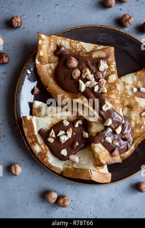 Pfannkuchen mit Nutella und Haselnüsse. Hausgemachte dünne Crepes für Frühstück oder Dessert, aus der Nähe. Stockfoto