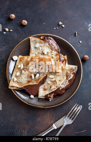 Pfannkuchen mit Nutella und Haselnüsse. Hausgemachte dünne Crepes für Frühstück oder Dessert, aus der Nähe. Stockfoto