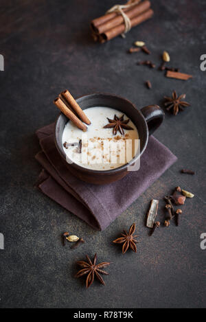 Traditionelle indische Masala Chai Tee in Keramik Tasse mit Zutaten. Würziger schwarzer Tee mit Milch (Masala) auf rustikalen dunklen Hintergrund. Stockfoto