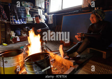 Ama Taucher im Neoprenanzug entspannen, plaudern und Aufwärmen am Kamin in ihren traditionellen Holzhütte nach einem Tauchgang im Meer, Mie, Japan Stockfoto