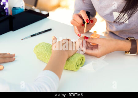 Frau Hände empfangen Sie sich keine Maniküre in Beautysalon, draußen Schönheit Festival. Nagel Einreichung Stockfoto