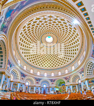 MOSTA, MALTA - 14. JUNI 2018: das Innere der riesigen Basilika der Himmelfahrt Mariens (Rundbau) mit reich verzierten gewölbten Nischen, schönen Altar ein Stockfoto