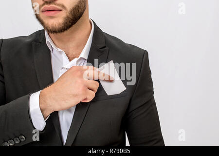 Schnittansicht der Jungen bärtigen Mann hält weiße Stück Stoff. Er steckte ihn in die Tasche. Junge Mann trägt. Auf weissem Hintergrund. Stockfoto