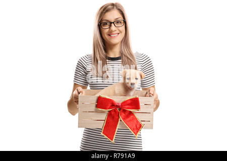 Junge Frau mit einem kleinen Welpen in einer Holzkiste mit einer roten Schleife auf weißem Hintergrund Stockfoto