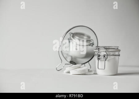 Schöne minimalistische konzeptionelle Alle weissen Komposition - Wattepads, transparente Jar und runden Spiegel, alles Weiß, mit metallischen Details Stockfoto