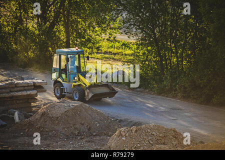 Kleine Bagger Autos auf einer staubigen Straße durch den Bau im Abendlicht Stockfoto