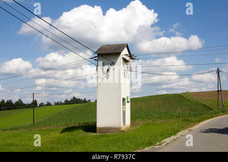 Alter Trafo in der Landschaft mit grünen Wiese und Wolken am blauen Himmel im Frühjahr am Tag Stockfoto