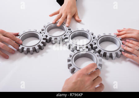 Geschäftsleute verbinden Zahnräder auf Schreibtisch Stockfoto