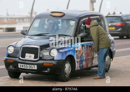 Black Cab vom Typ London, TX4, Taxicab, hackney-Wagen, auf den Straßen von Blackpool, Großbritannien mit gesponserter Werbung. Stockfoto