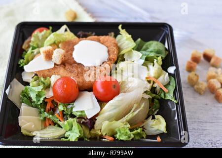 Close up Caesar Salat mit hausgemachten Croutons, Hühnerfleisch, Parmesan und Caesar Dressing in großen schwarzen Platte - Bild Stockfoto