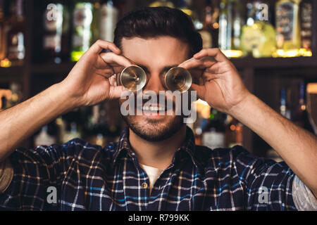 Junge Barkeeper stehen an der Theke, die Augen mit jigger Fröhliche close-up Stockfoto