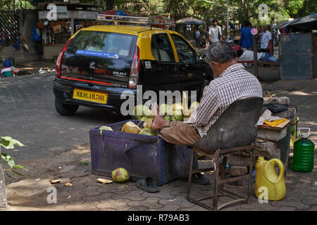 Ein Mann schlafen vor seinem Kokosnüsse für Verkauf in einer Straße in Mumbai, Indien. Stockfoto