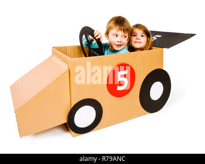 Foto von einem Bruder und Schwester Fahren ihrer hausgemachten Karton Auto über weißen Hintergrund. Stockfoto