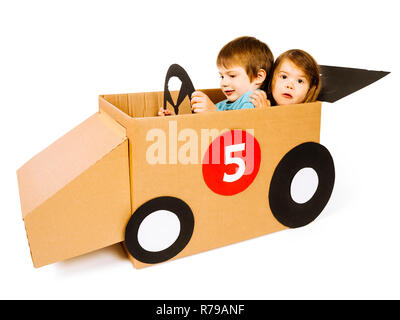 Foto von einem Bruder und Schwester Fahren ihrer hausgemachten Karton Auto über weißen Hintergrund. Stockfoto