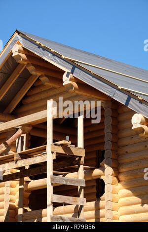 Prozess der Holz- Haus gerade Dachneigung Montage an Wolkenlosen sonnigen Tag Vorderansicht. Holz haus Bau Stockfoto