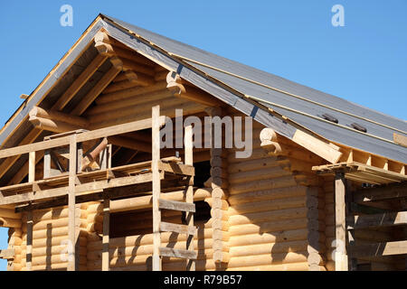 Prozess der Holz- Haus gerade Dachneigung Montage an Wolkenlosen sonnigen Tag Vorderansicht. Holz haus Bau Stockfoto